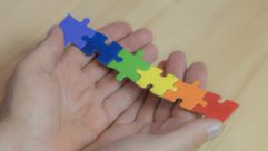 Child holding rainbow colored puzzle pieces
