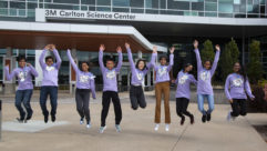 9 finalists from the Young Scientist Challenge in a line, jumping in the air together.
