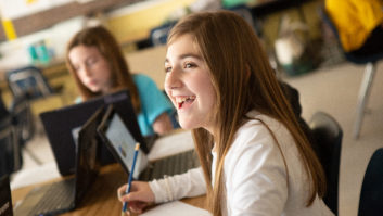 Smiling middle-school female student at table with other student in background for article on student choice