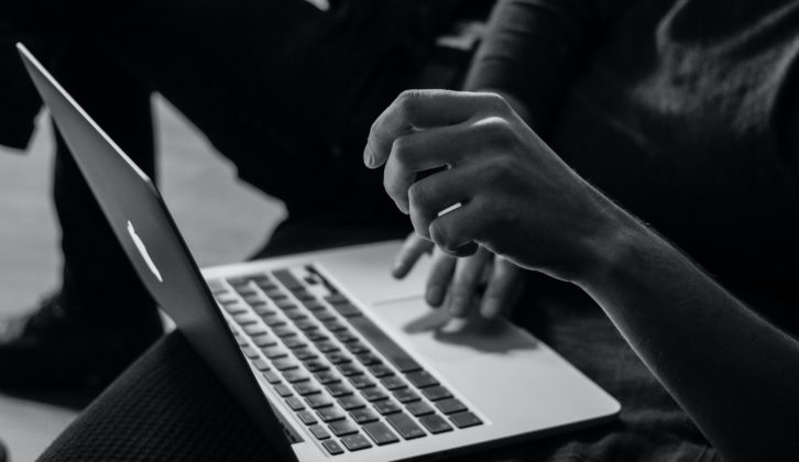 Black-and-white photo of hands on a laptop computer for implementing online tutoring article