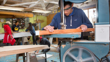 Student using machine and wood for boat-building project in CTE classroom for article on how CTE helps engage students