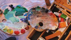 2 palettes with messy paint and brushes for article on teachers as artists and autonomy and creativity