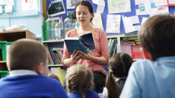 Teacher at front of classroom reading a book to young students for article on storytelling to build students' resilience