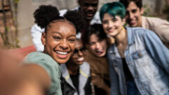 Young Black woman taking selfies with friends in the street for article on wellness program in higher education