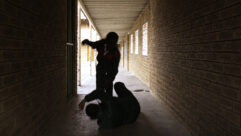 Two school kids fight in a dark passageway of their school, almost silhouette, for article on school safety measures