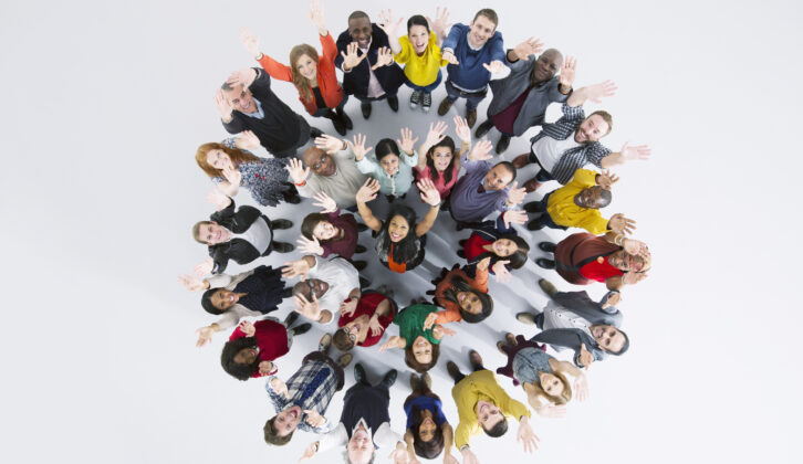 circle within circle of enthusiastic people with arms in the air for article on nuances of belonging
