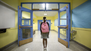 Rear view of eleven-year-old girl looking down school corridor for article on school safety