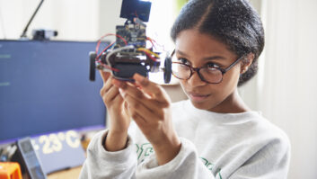 Black teenage girl with glasses holding up robot-like piece of technology for article on embrace tech