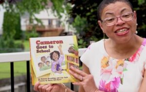 photo of Black woman wearing glasses holding children's book for Smithsonian Institution teacher toolkit