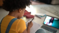 Rear view of a elementary age girl studying watching online classes for article on virtual tutoring