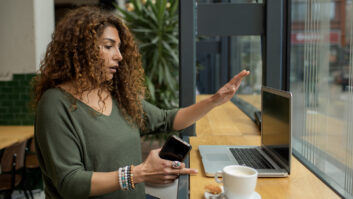Ethnic adult female using AI on a laptop computer and holding a smartphone for article on AI tools in schools