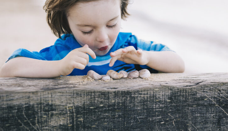 Small child behind a wall counting a row of snails atop the wall for article on pictorial representations in math