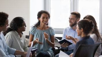 Several diverse adults sitting around in a circle talking in a work environment.