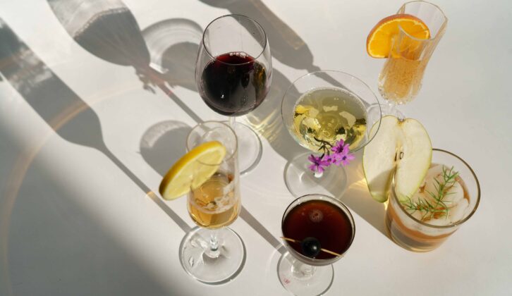 Six wine and cocktail glasses casting shadows on a white background (Checking in on trends, resources for wine and beverage professionals)